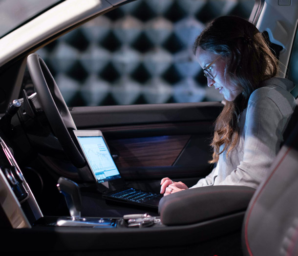 Frau arbeitet mit Laptop in einem parkenden Auto