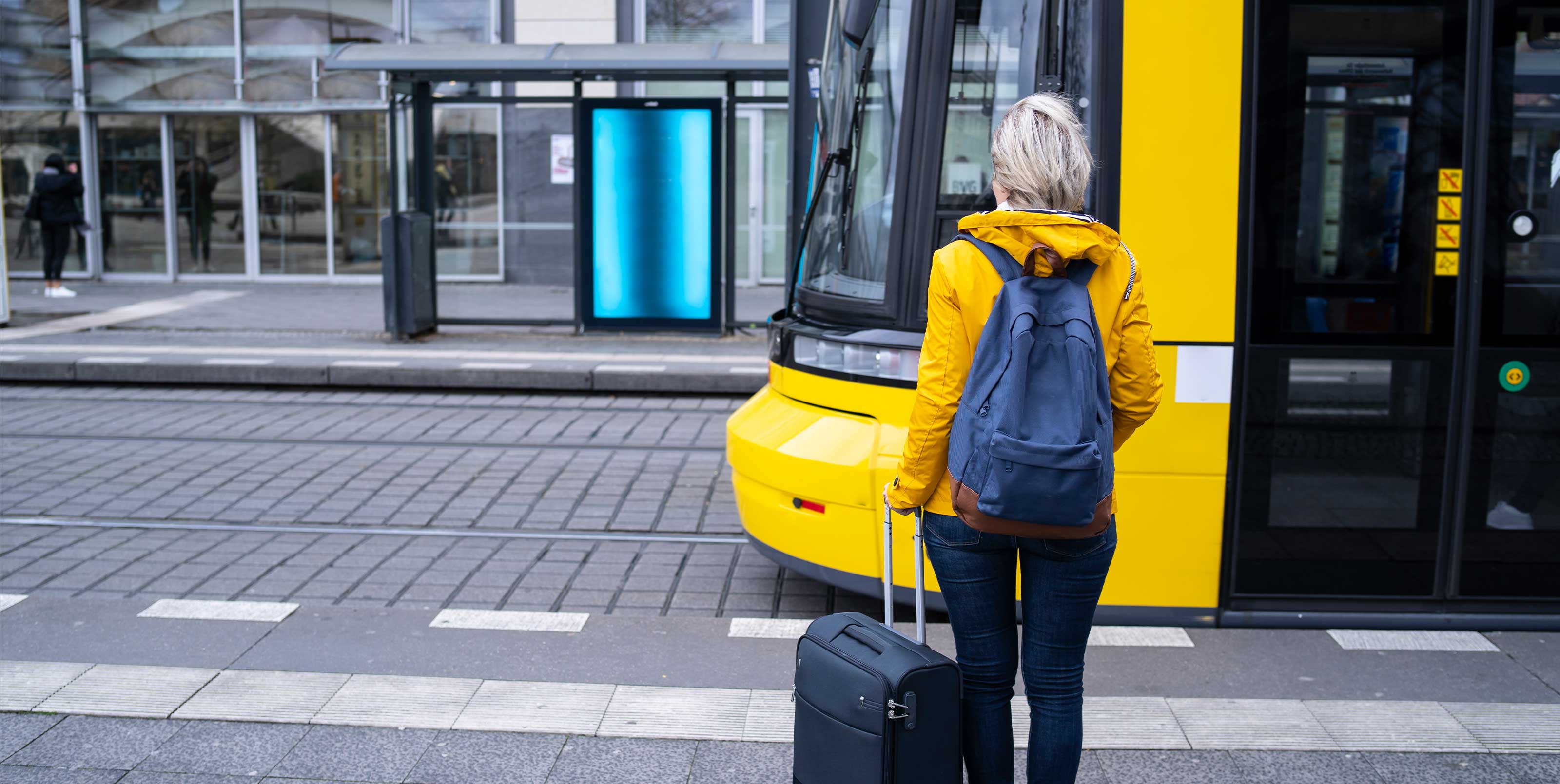 Woman with suitcase walks towards streetcar
