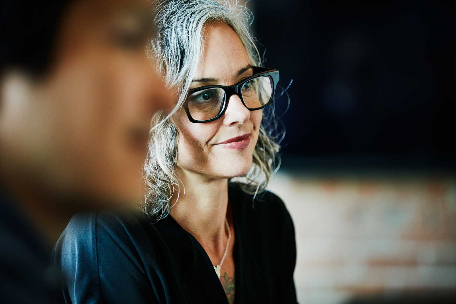 Smiling woman with striking glasses listens