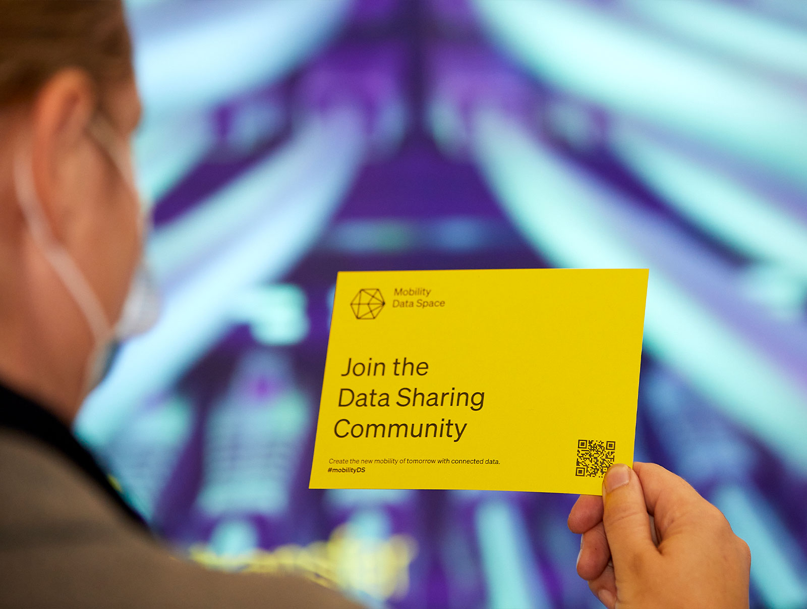 Person holds up yellow flyer with inscription: Join the Data Sharing Community