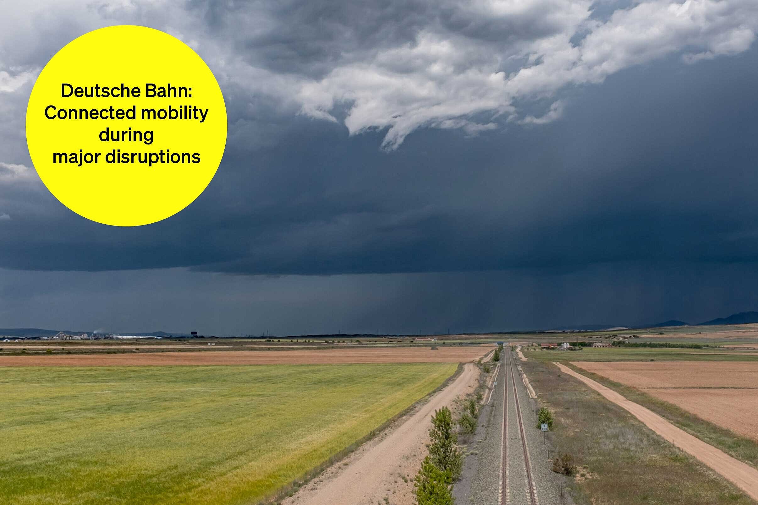 Railroad tracks between fields in cloudy weather - text module in round tile: Deutsche Bahn Mobilität vernetzt: Multimodal major disruption information